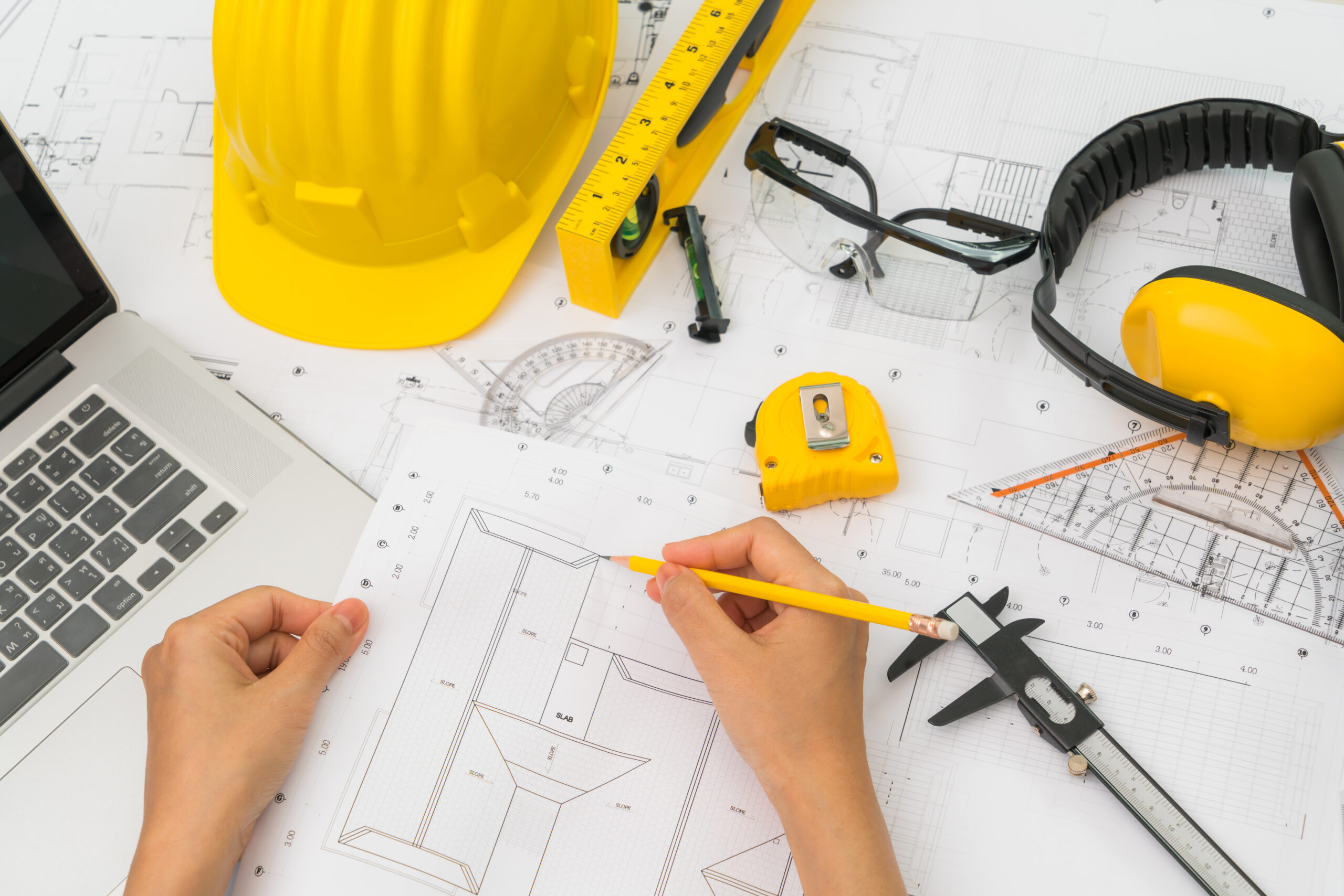 hand-construction-plans-with-yellow-helmet-drawing-tool designing