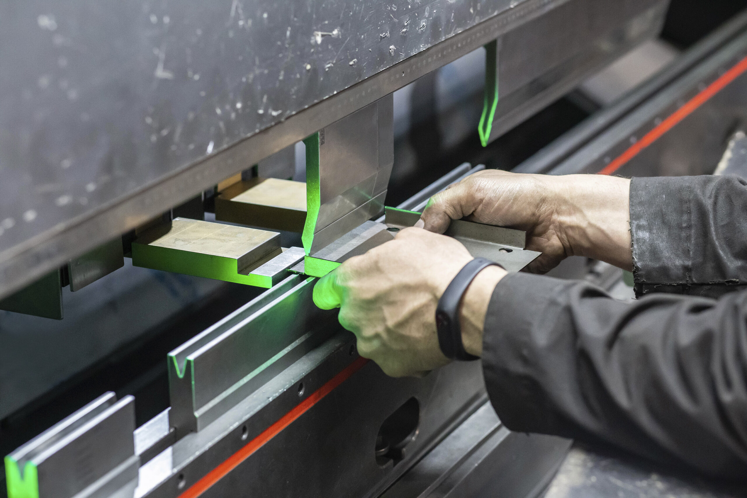 worker-holds-part-cnc-bending-machine metal bending